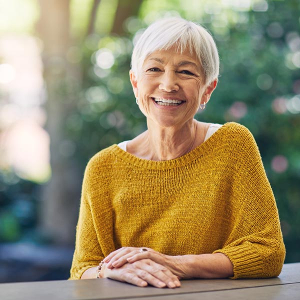 Shot of a happy senior woman sitting at a table in her backyard