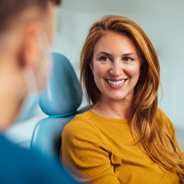 Smiling red haired woman listening to her dentist while sitting in his office