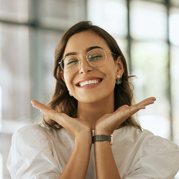 Cheerful business woman with glasses posing with a smile in an office