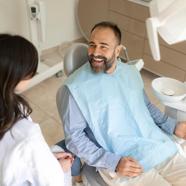 Happy male patient talking to his dentist in clinic
