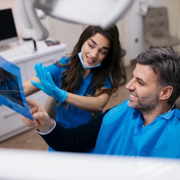 Dentist showing teeth x-ray to adult patient at dentist