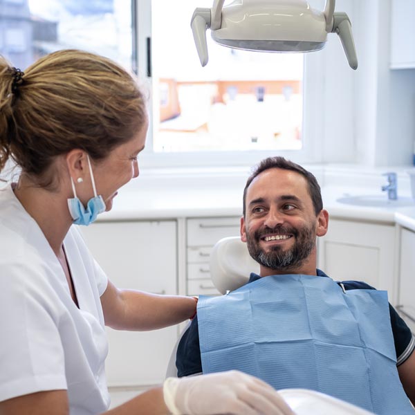 A patient in a dental chair smiles at a dentist during the appointment