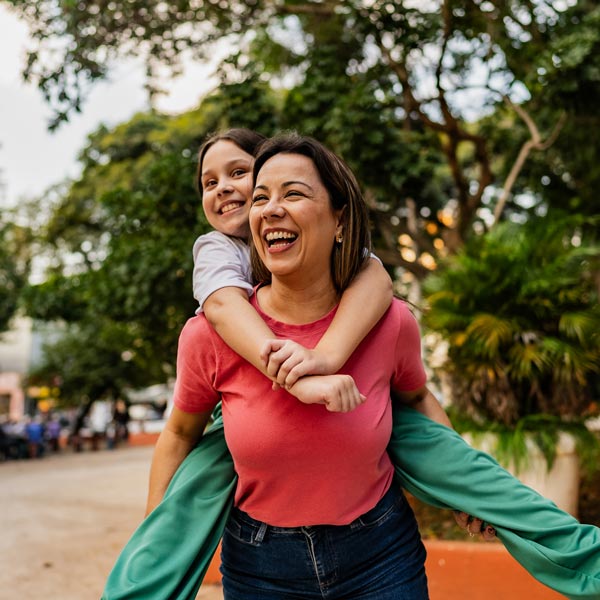 Mother and daughter doing piggyback outdoors